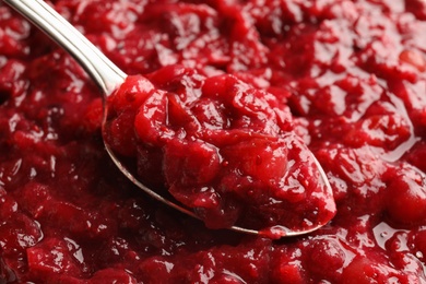 Photo of Spoon and tasty cranberry sauce, closeup view