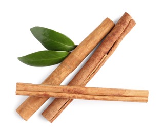 Photo of Cinnamon sticks and green leaves isolated on white, top view