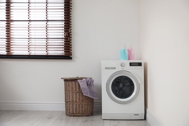 Photo of Modern washing machine and laundry basket indoors