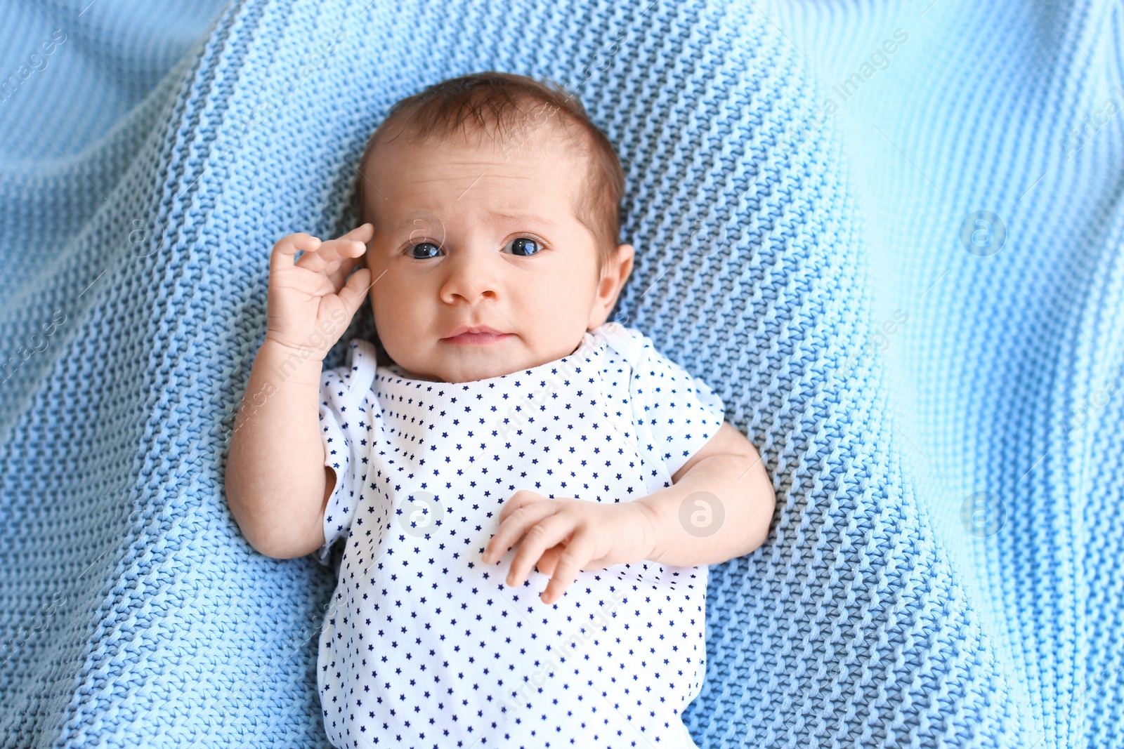 Photo of Cute little baby lying on light blue plaid, top view