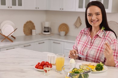 Photo of Beautiful overweight woman having healthy meal at table in kitchen