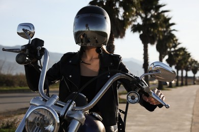Woman in helmet riding motorcycle on sunny day