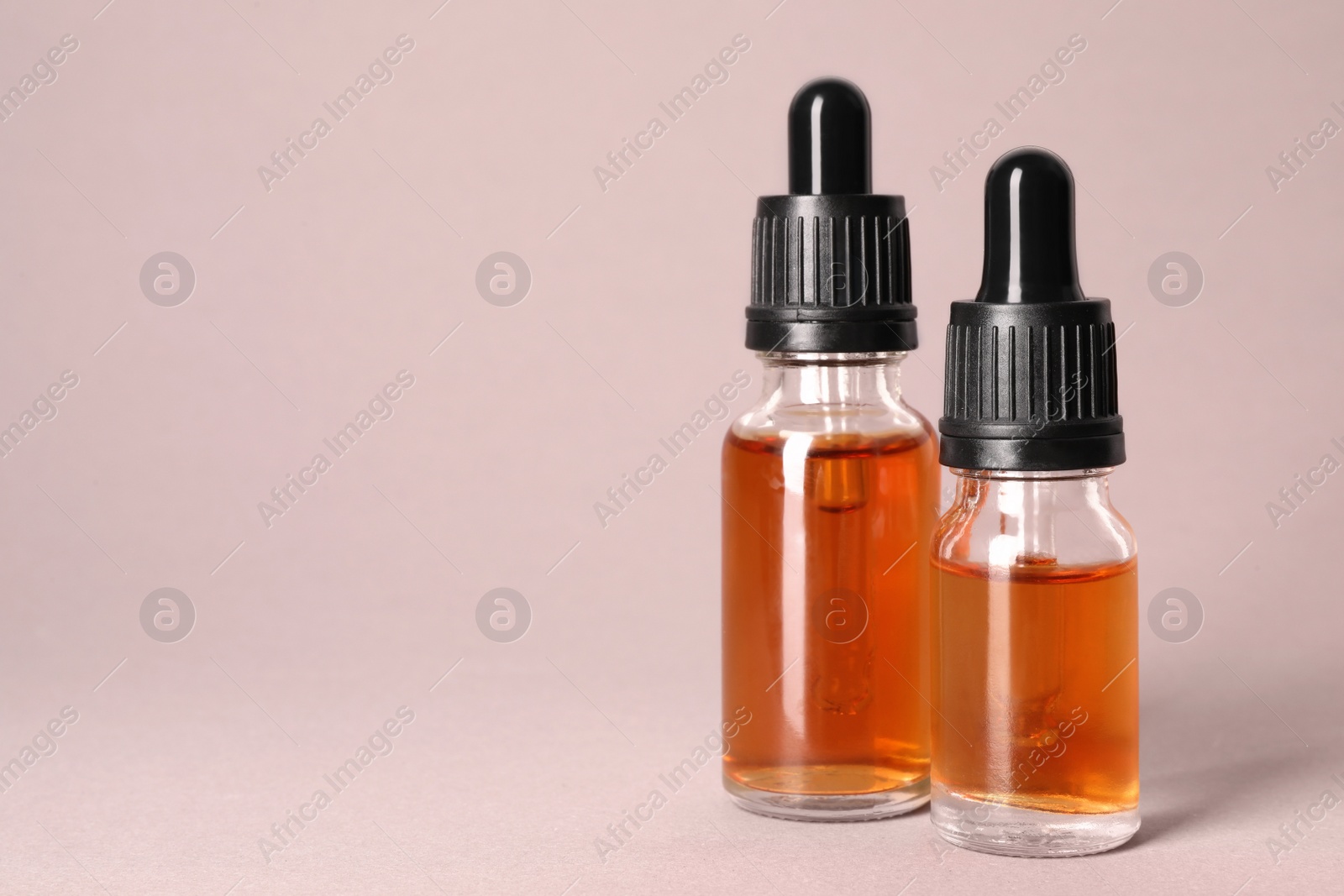 Photo of Cosmetic bottles of essential oils on color background. Space for text