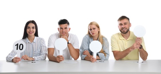 Panel of judges with different emotions holding blank signs at table on white background. Space for text