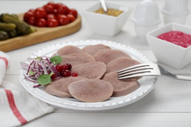 Tasty beef tongue pieces, berries and red onion on white wooden table, closeup