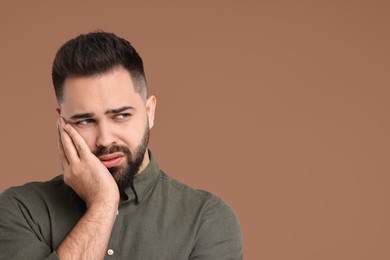 Portrait of sad man on brown background, space for text