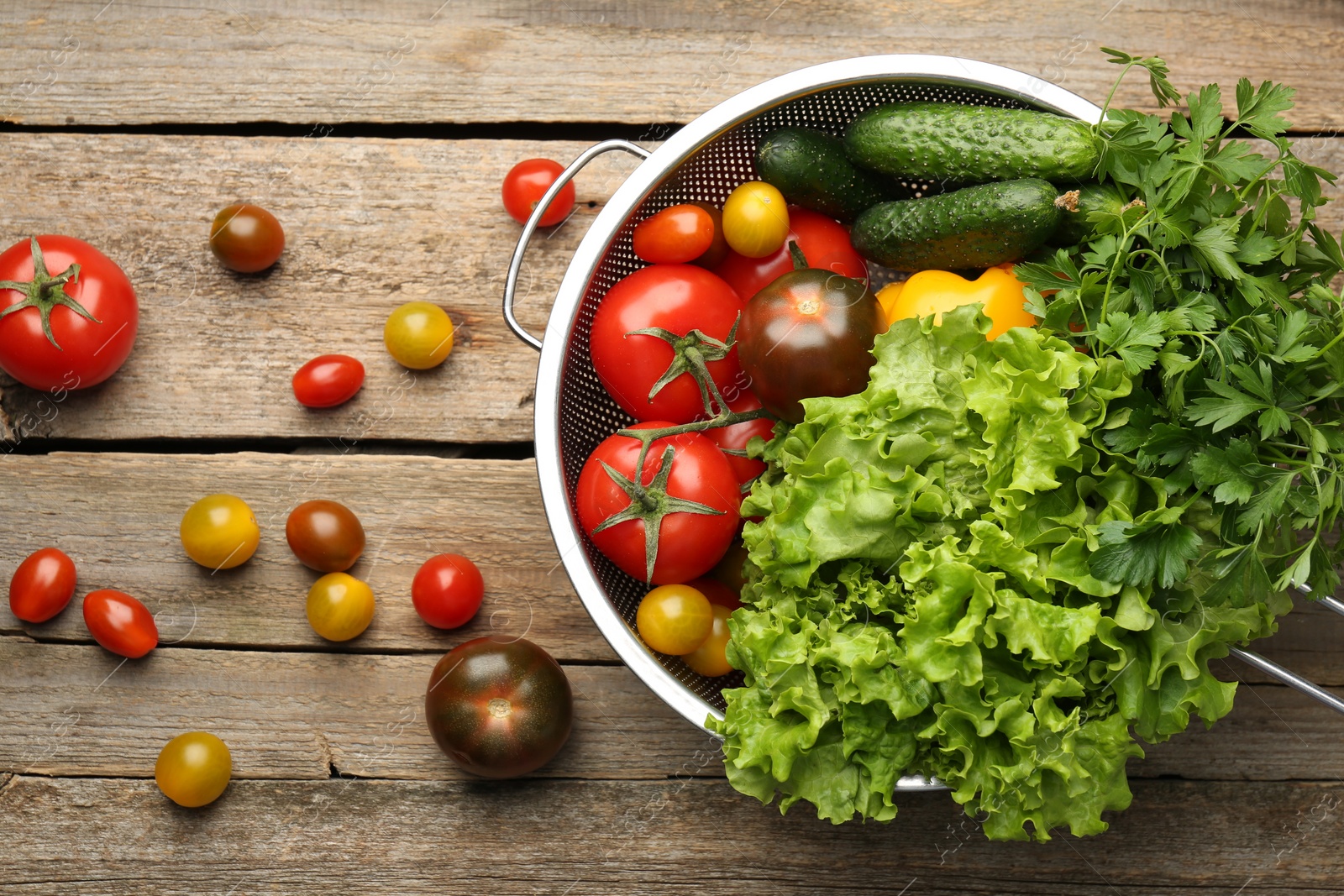 Photo of Fresh vegetables in colander on wooden table, flat lay