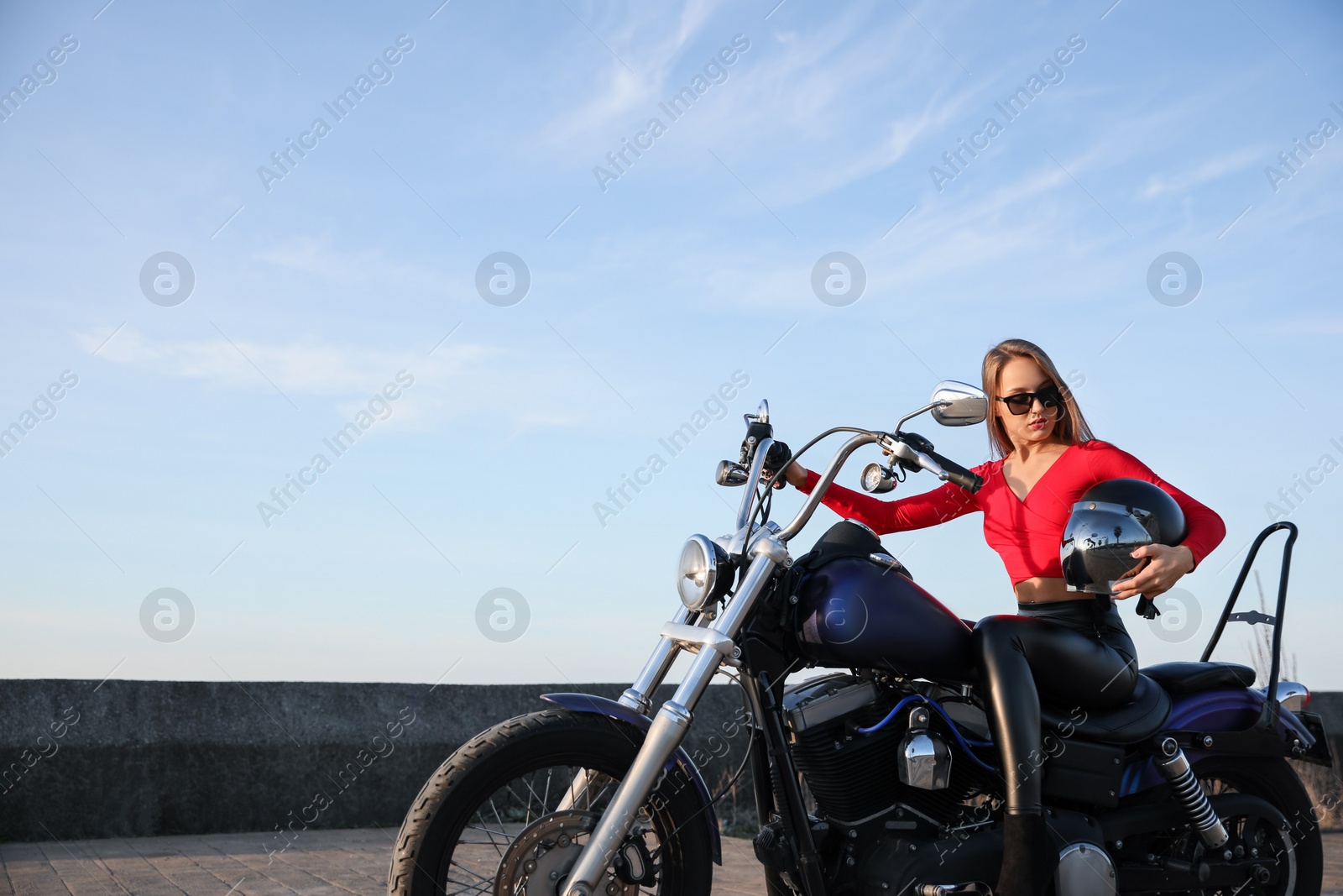 Photo of Beautiful young woman with helmet sitting on motorcycle outdoors