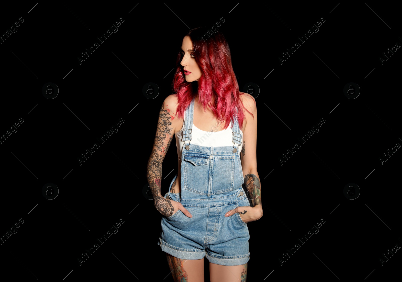 Photo of Beautiful woman with tattoos on body against black background