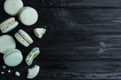 Delicious light blue macarons on black wooden table, flat lay. Space for text