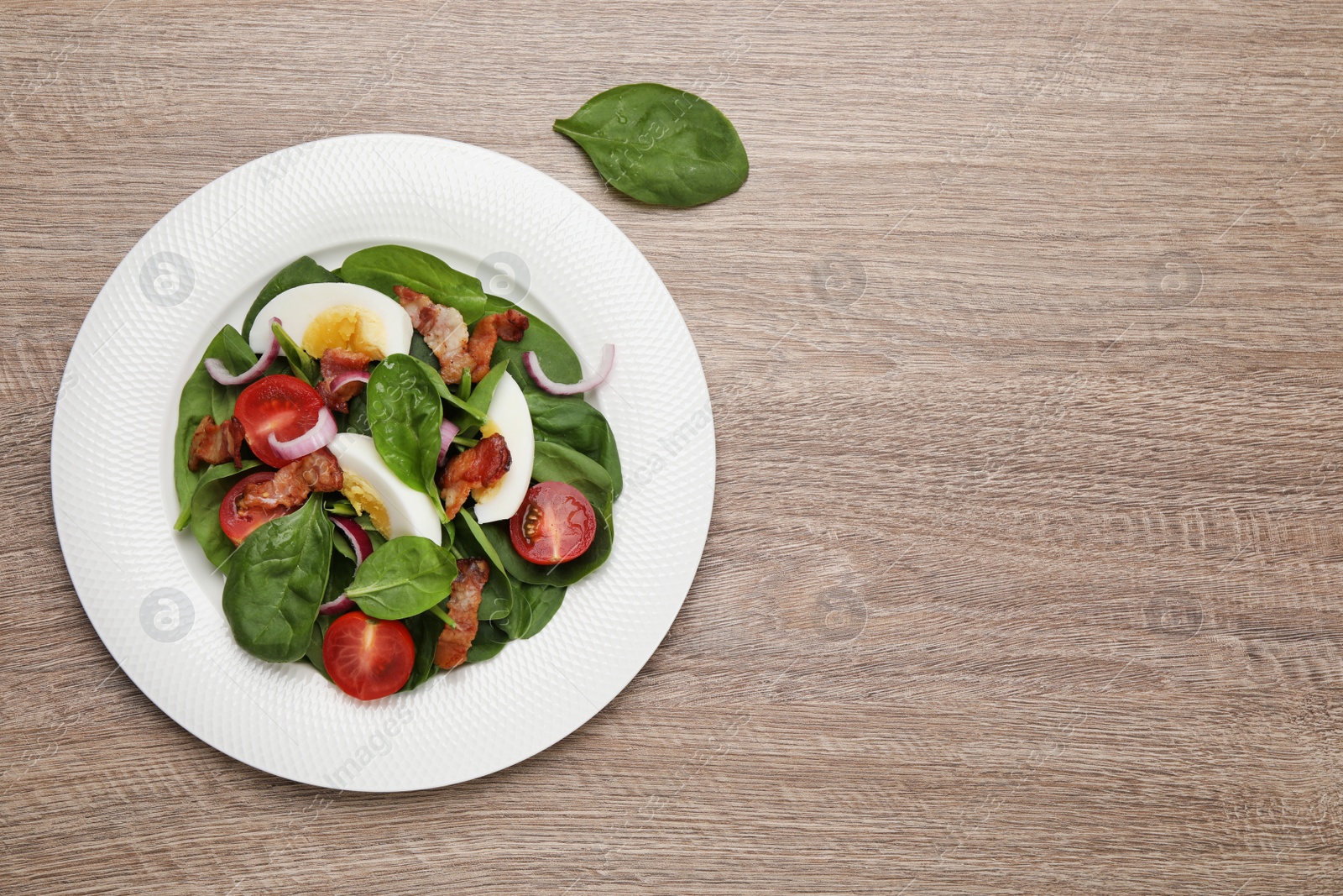 Photo of Delicious salad with boiled egg, bacon and vegetables on wooden table, flat lay. Space for text