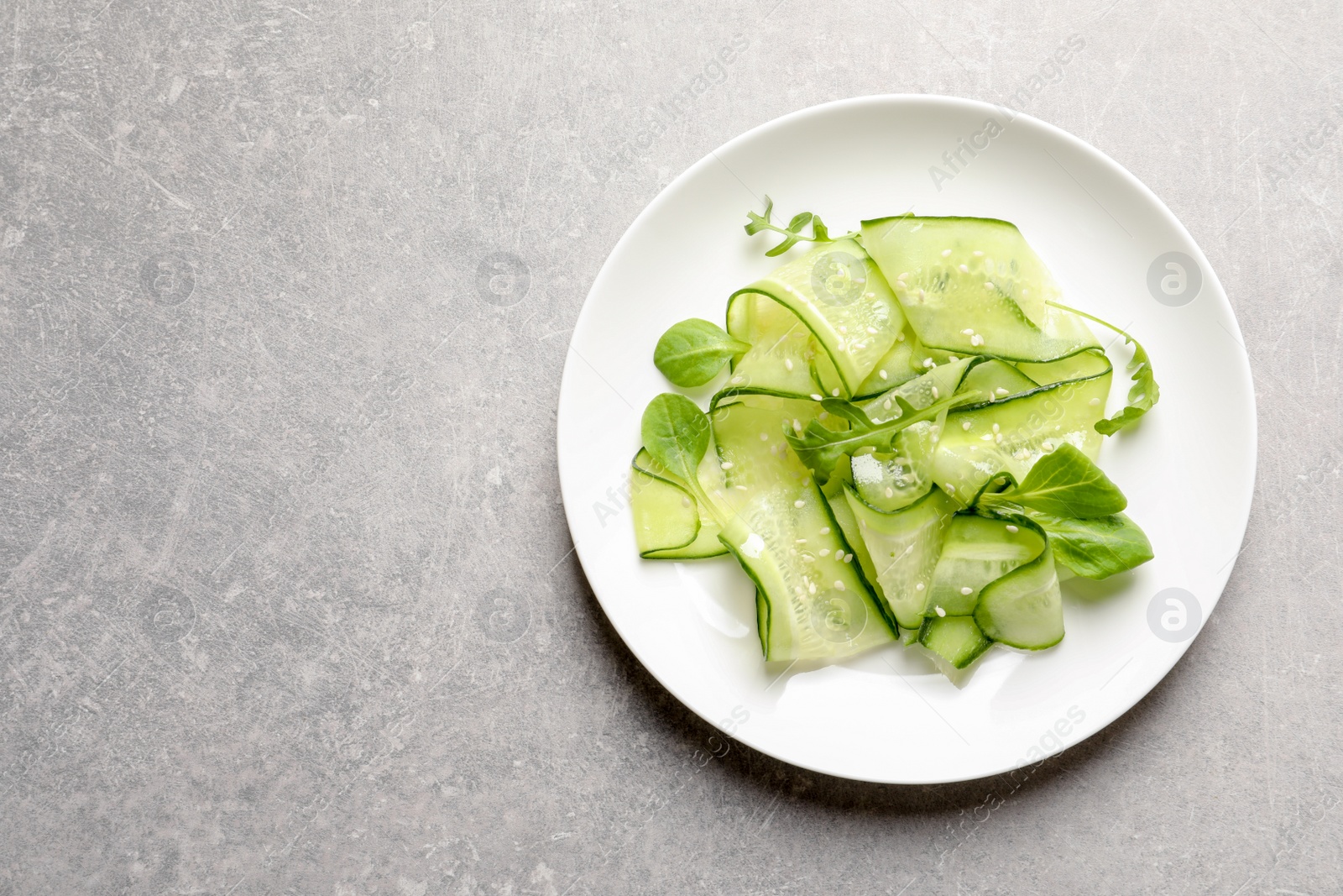 Photo of Plate with delicious cucumber salad on grey background, top view. Space for text