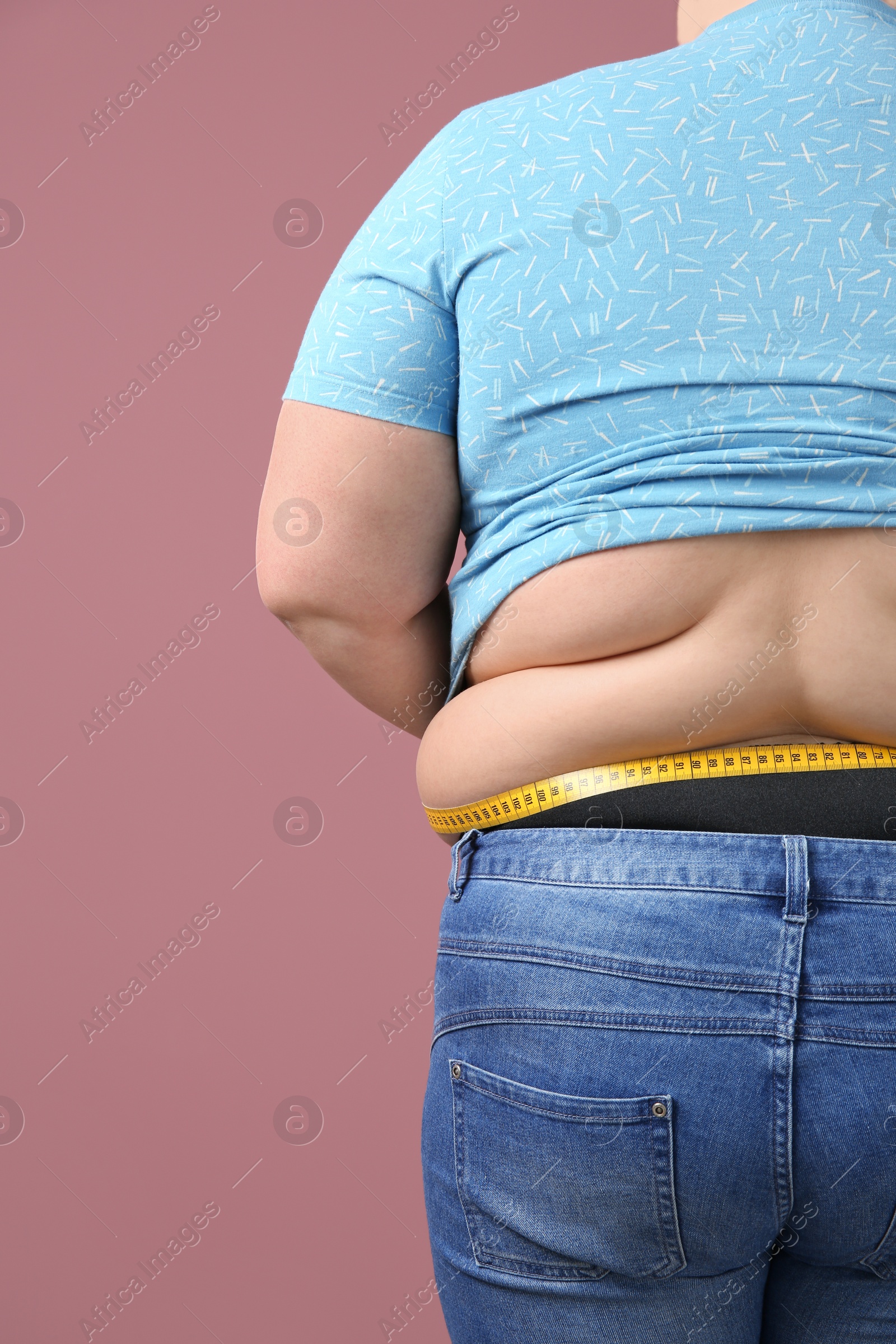 Photo of Overweight woman with measuring tape on color background