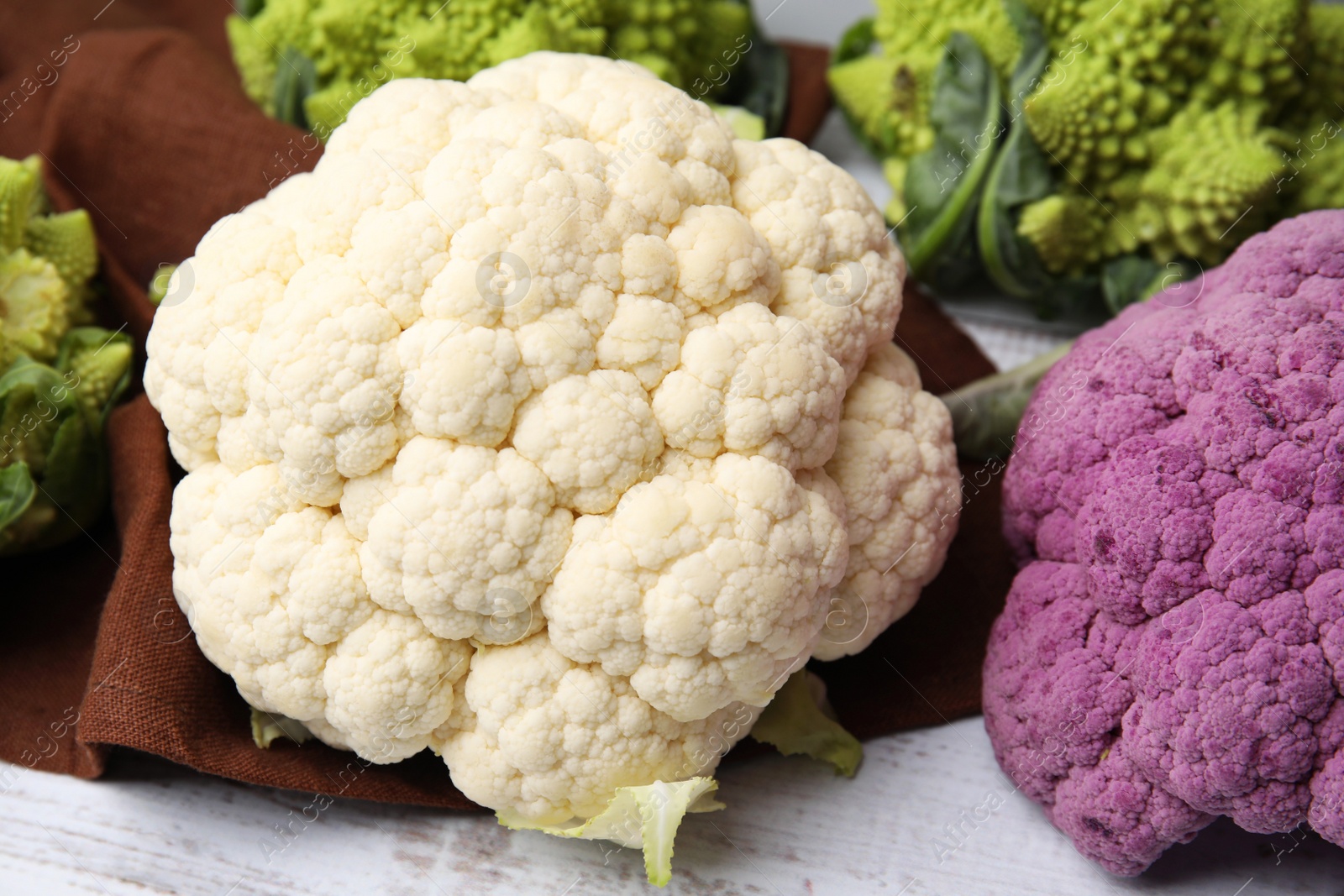 Photo of Different fresh cabbages on white wooden table, closeup