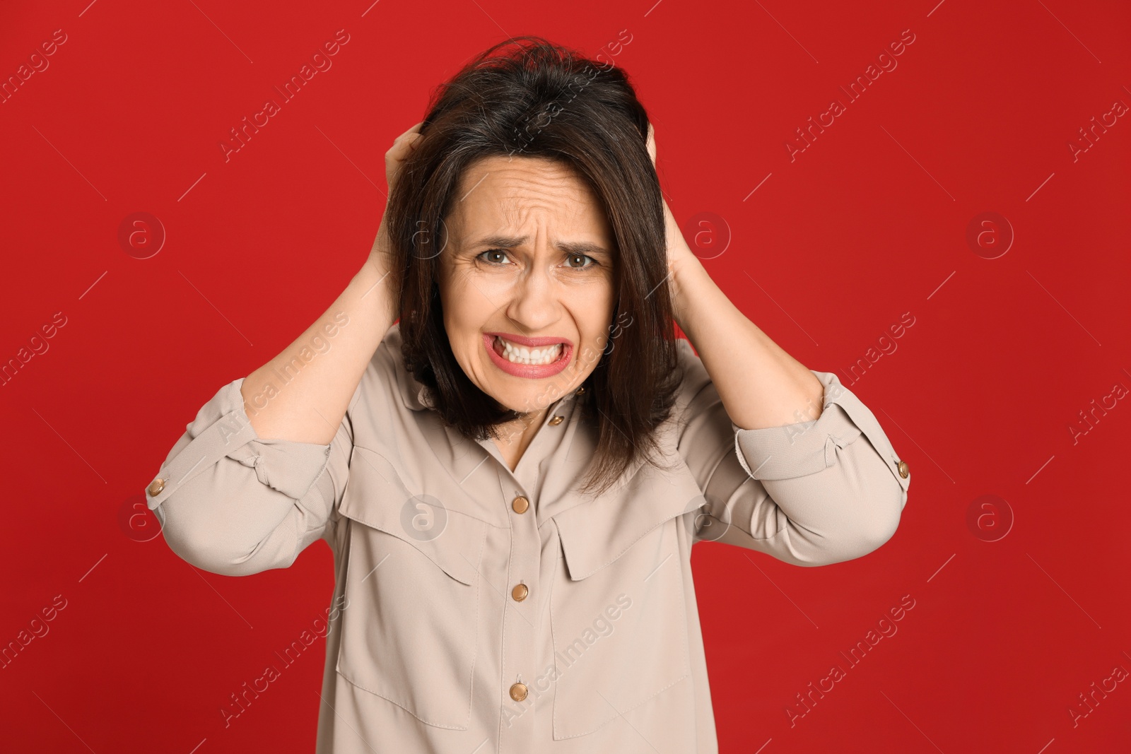 Photo of Portrait of angry woman on red background. Hate concept