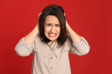 Photo of Portrait of angry woman on red background. Hate concept