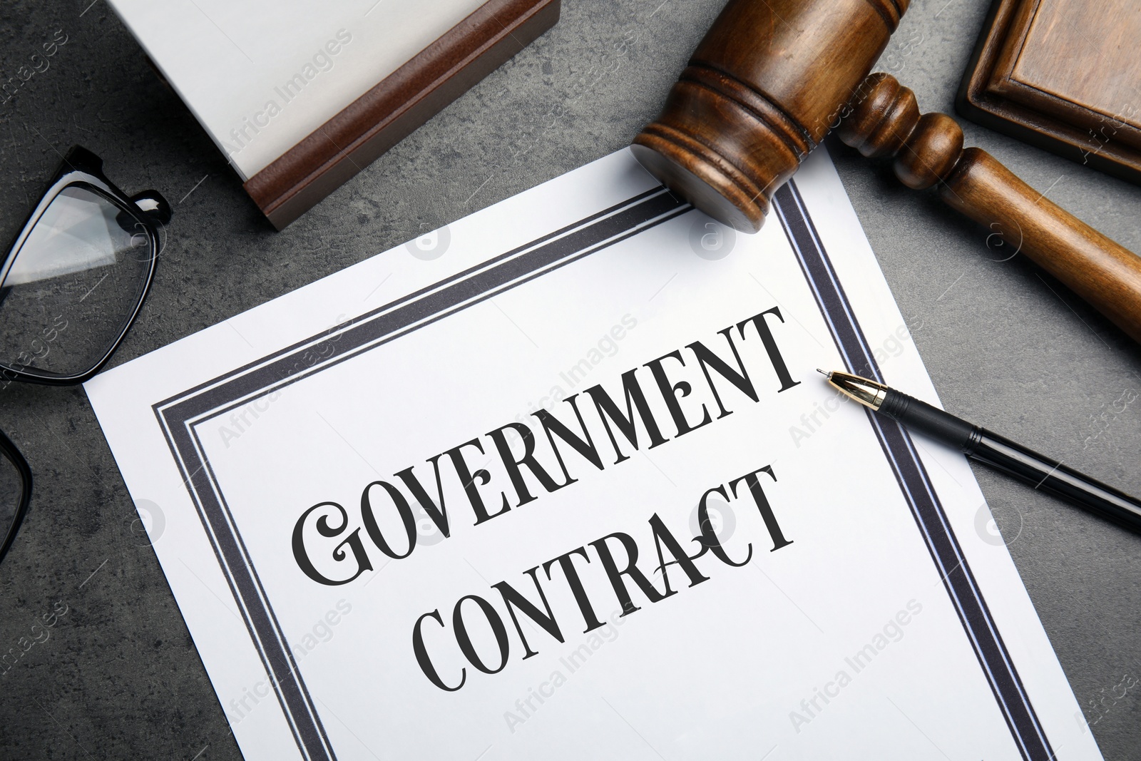 Image of Government contract, wooden gavel, pen and eyeglasses on grey table, flat lay