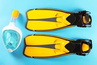 Pair of yellow flippers and diving mask on color background, top view