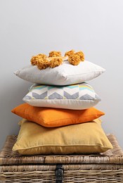 Soft pillows on wooden trunk near light grey wall