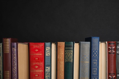 Photo of Stack of hardcover books on black background. Space for text