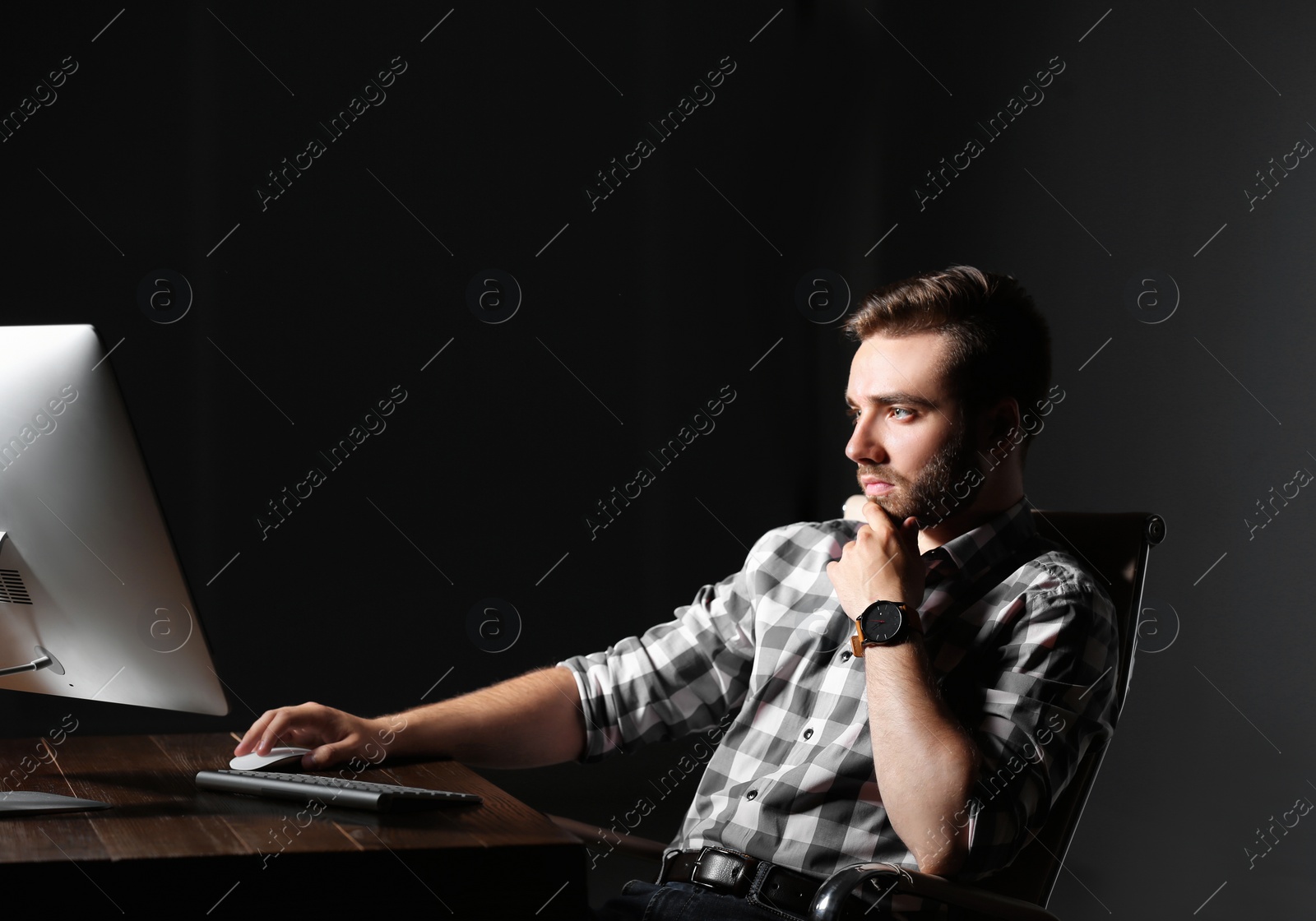 Photo of Concentrated young man working in office alone at night