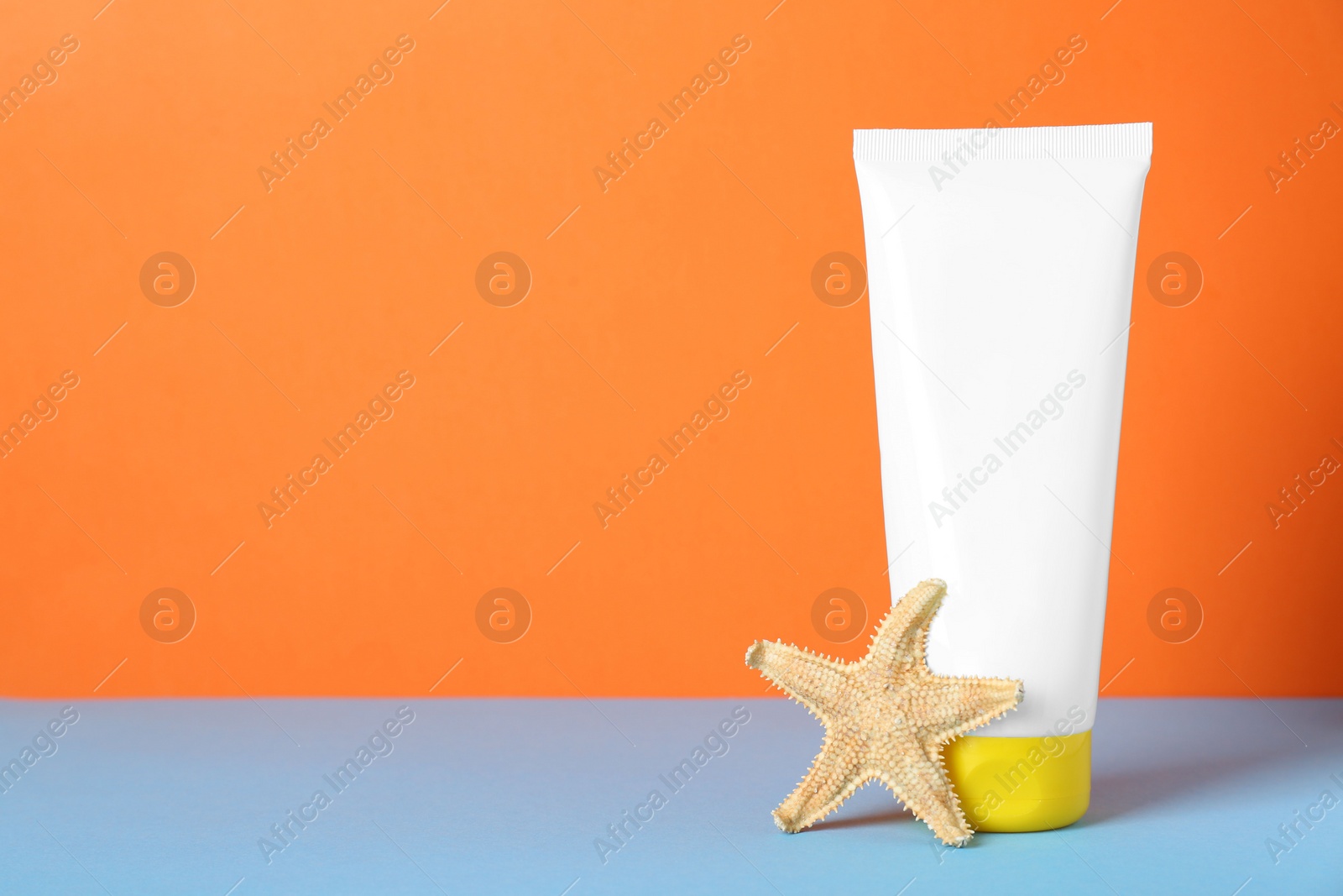 Photo of Suntan product and starfish on color background. Space for text