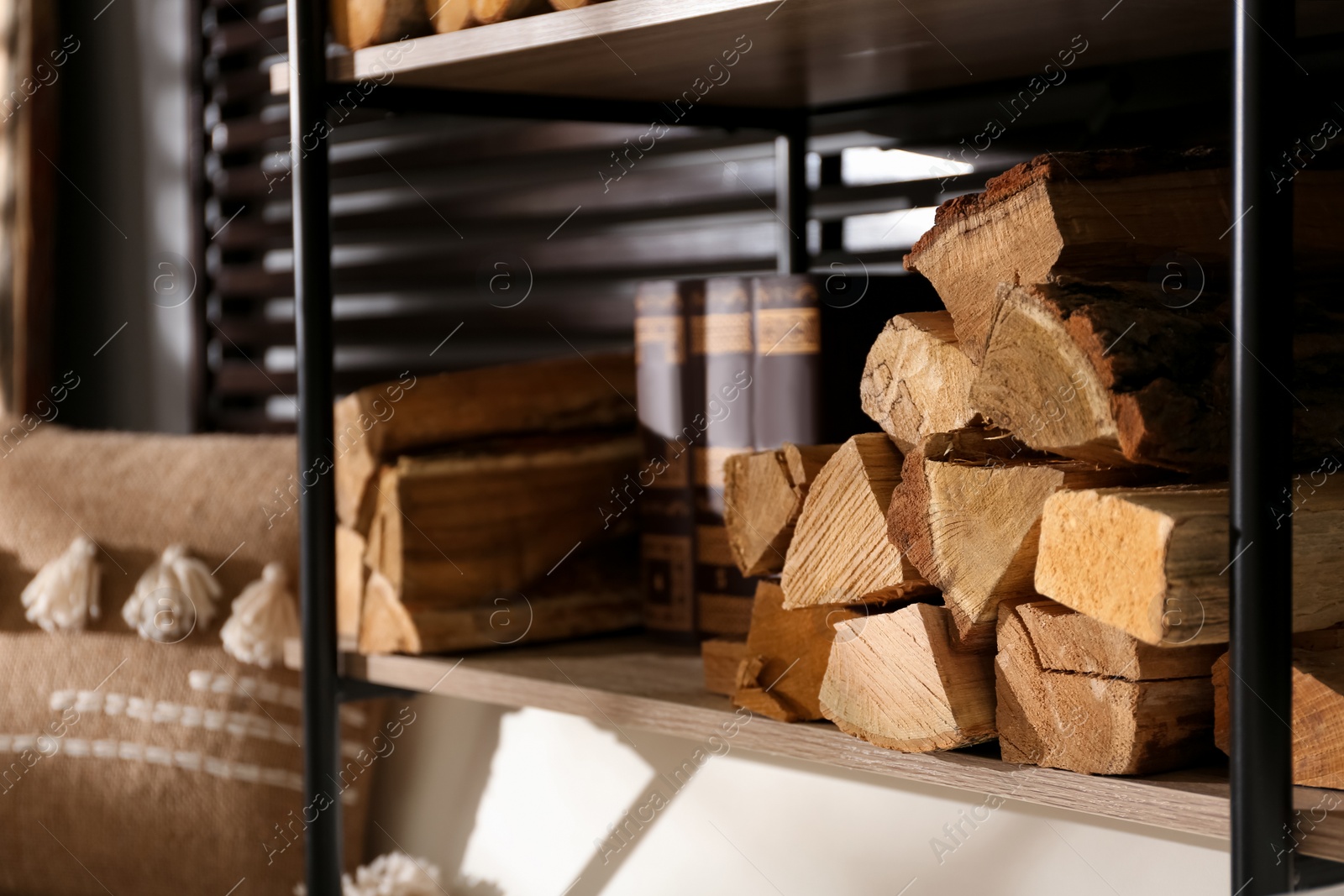 Photo of Shelving unit with stacked firewood near wall in room, closeup. Idea for interior design