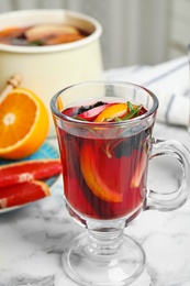 Tasty mulled wine with spices on white marble table