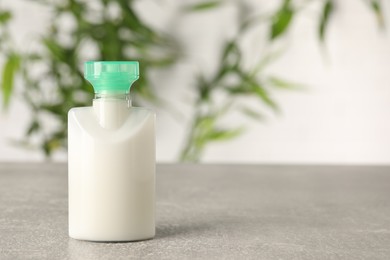 Photo of Mini bottle of cosmetic product on light grey table against blurred background. Space for text