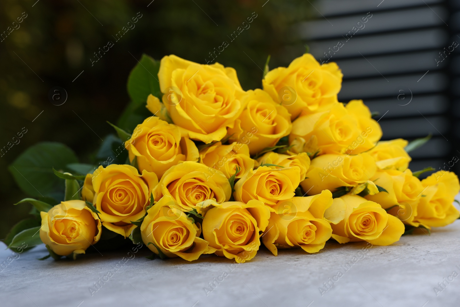 Photo of Beautiful bouquet of yellow roses on light table outdoors