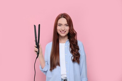 Photo of Beautiful woman with hair iron on pink background