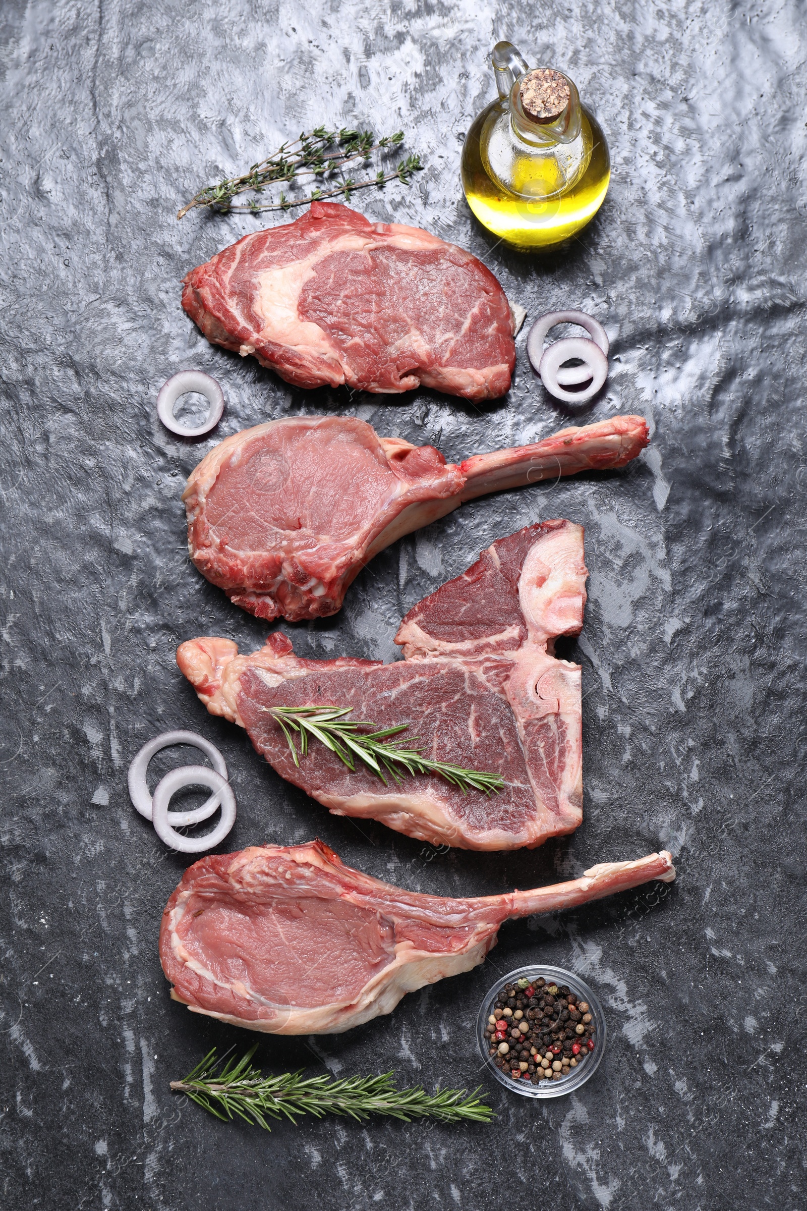 Photo of Fresh raw beef cuts and different spices on grey textured table, flat lay