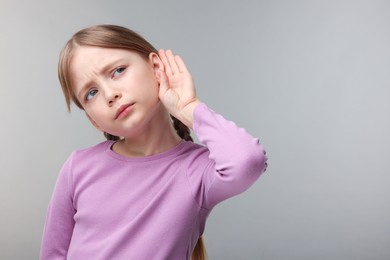 Photo of Little girl with hearing problem on grey background. Space for text