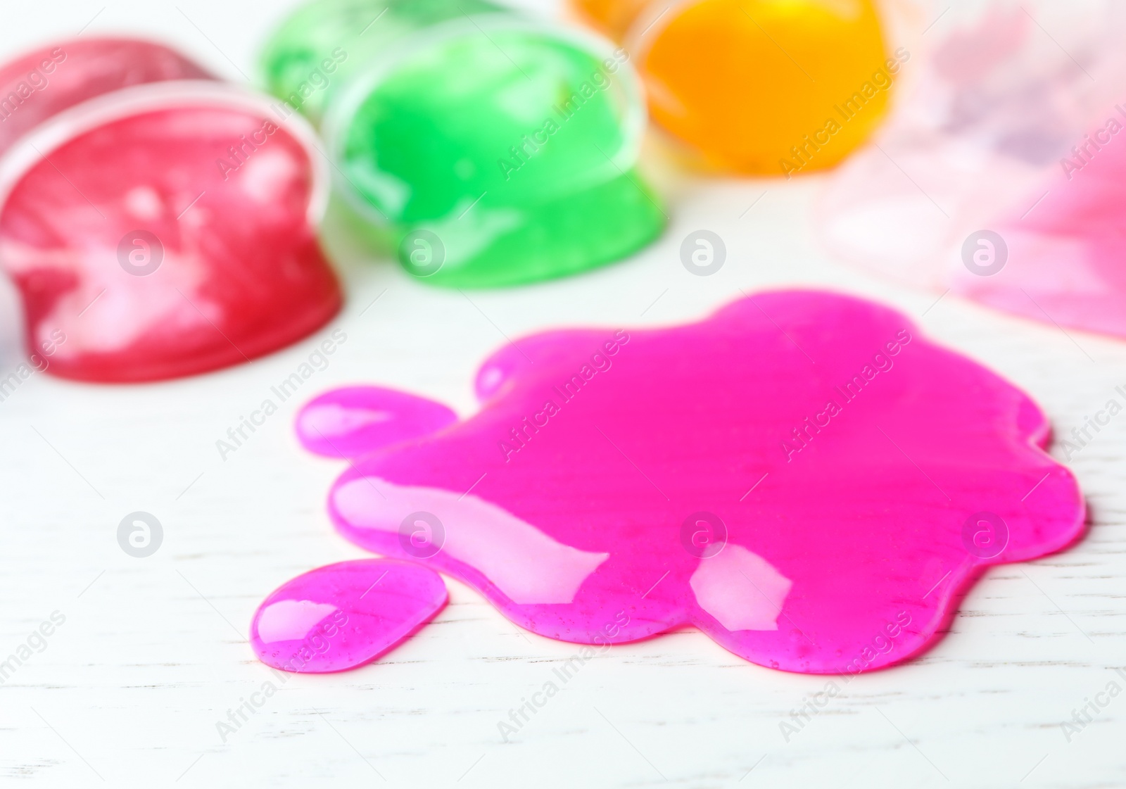 Photo of Splash of pink slime on white wooden background