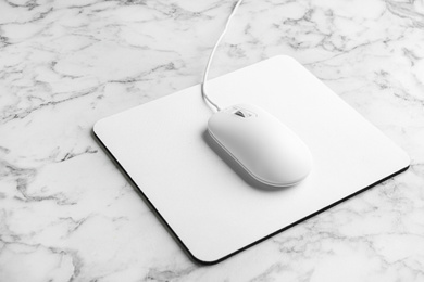 Modern wired optical mouse and pad on white marble table