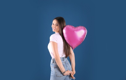 Photo of Portrait of young woman with heart shaped balloon on color background