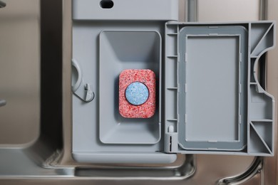 Photo of Open dishwasher door with detergent tablet, top view