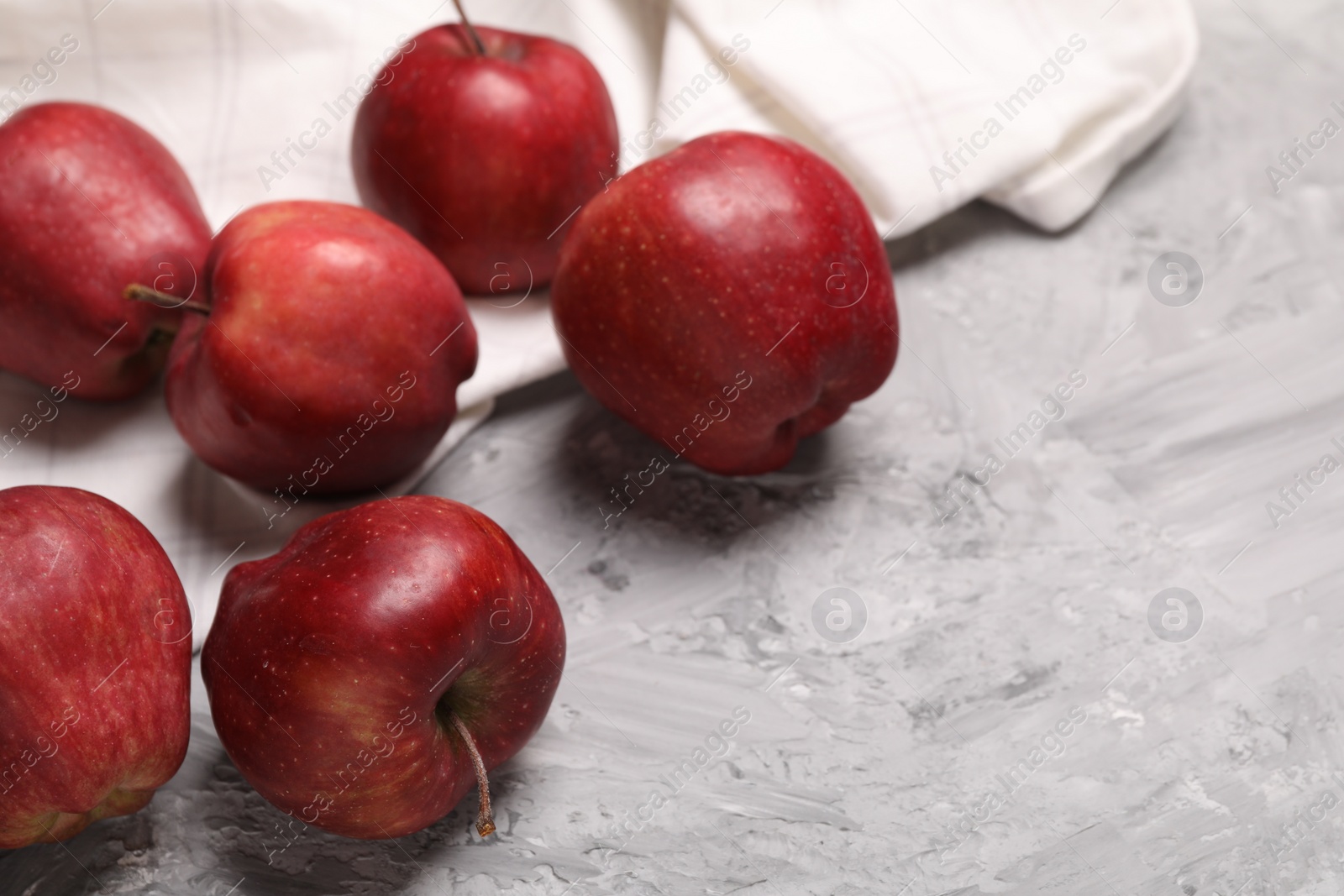 Photo of Fresh red apples on grey textured table, closeup. Space for text