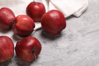 Fresh red apples on grey textured table, closeup. Space for text