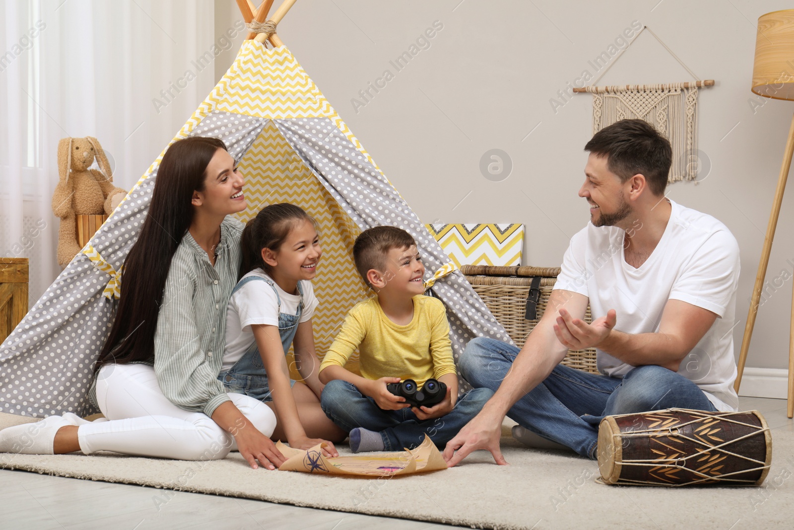 Photo of Happy family with treasure map near toy wigwam at home