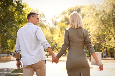 Happy couple walking along park on summer day