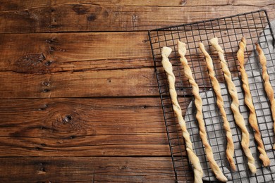 Photo of Rack with homemade breadsticks on wooden table, top view and space for text. Cooking traditional grissini
