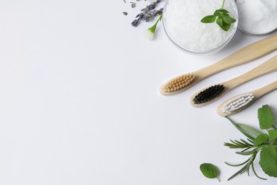 Flat lay composition with toothbrushes and green herbs on white background. Space for text