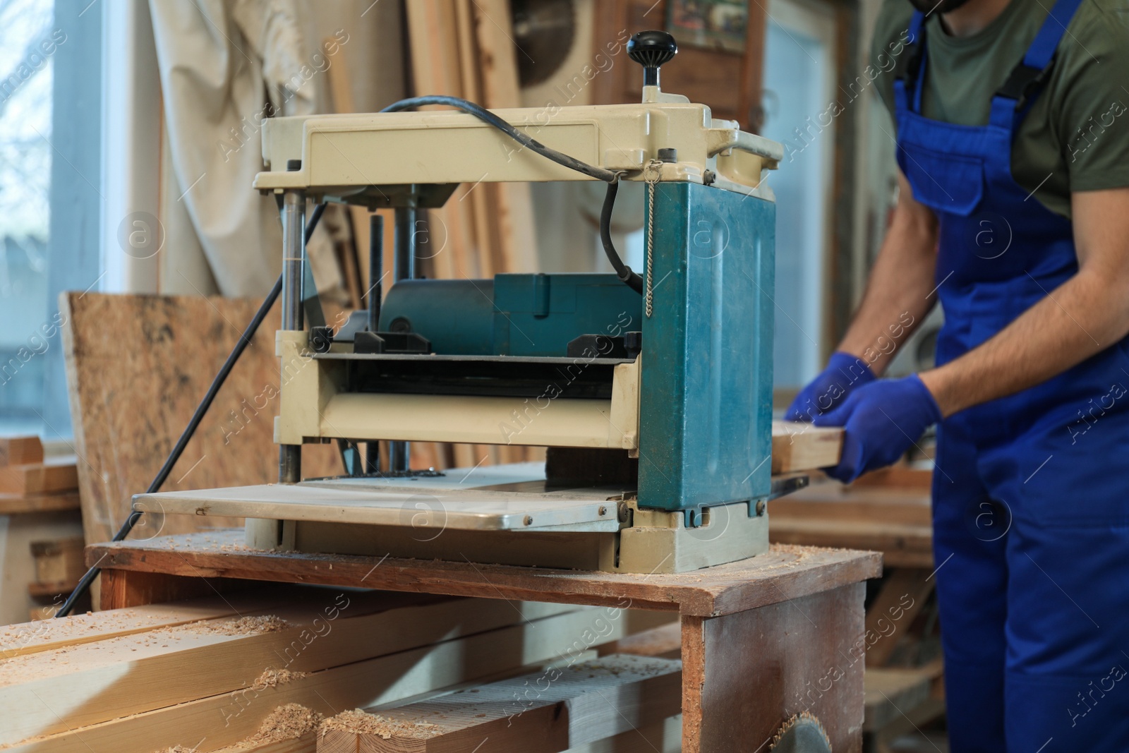 Photo of Professional carpenter working with grinding machine in shop, closeup