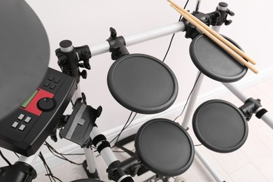 Photo of Modern electronic drum kit near white wall indoors. Musical instrument