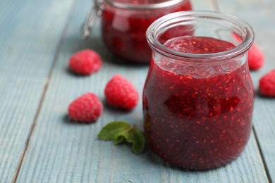 Delicious jam and fresh raspberries on light blue wooden table, closeup