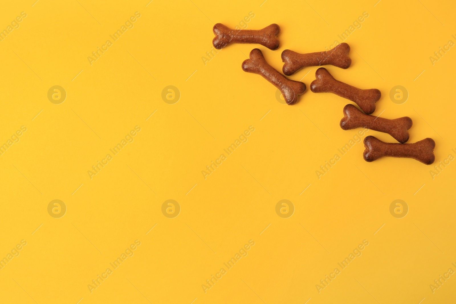 Photo of Bone shaped dog cookies on orange background, flat lay. Space for text