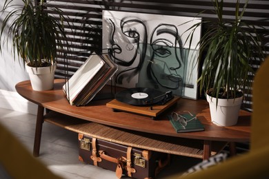 Photo of Stylish turntable with vinyl discs on table in room