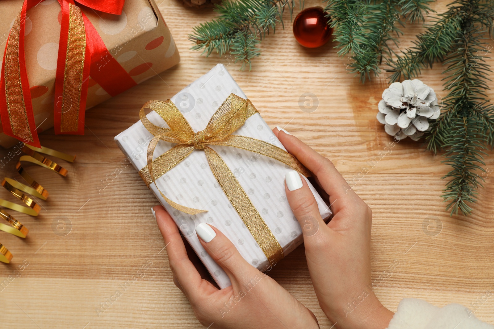 Photo of Woman with Christmas gift at wooden table, top view