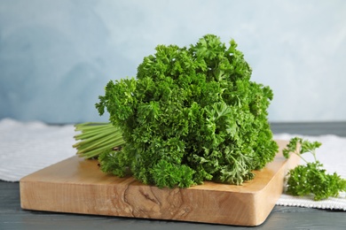 Wooden board with fresh green parsley on table